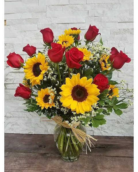 Bouquet of red roses and yellow sunflowers in a glass vase