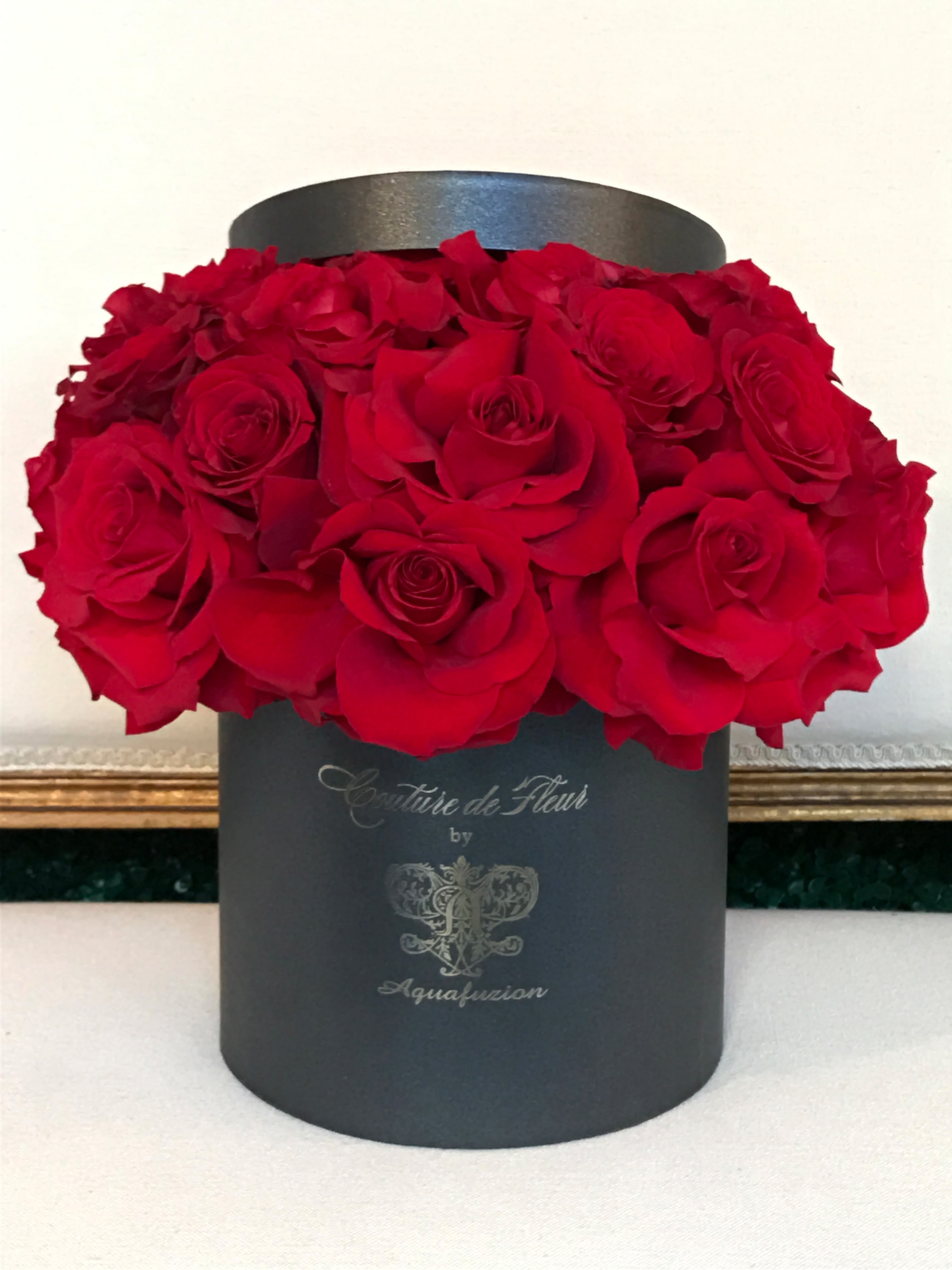 Red roses arranged in a black round hat box