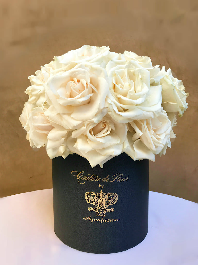 White roses arranged in a black cylindrical box