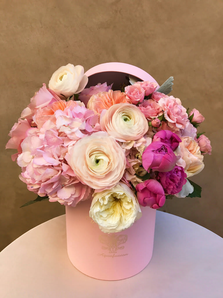 Pink and cream flower arrangement in a round hatbox