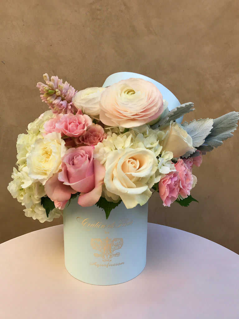 Pastel bouquet of roses, ranunculus, and hydrangeas in a light blue box