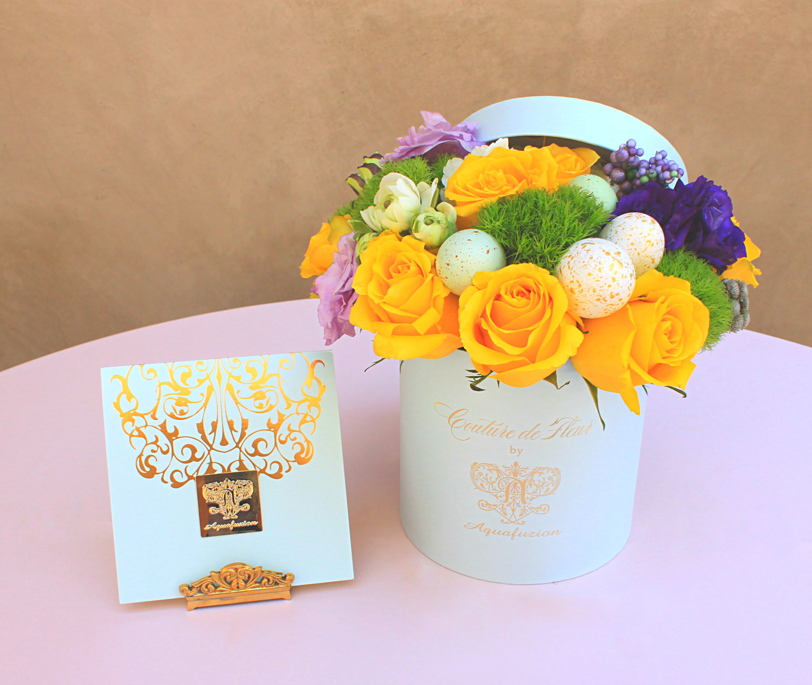 Yellow roses and purple flowers in a white hat box with decorative eggs