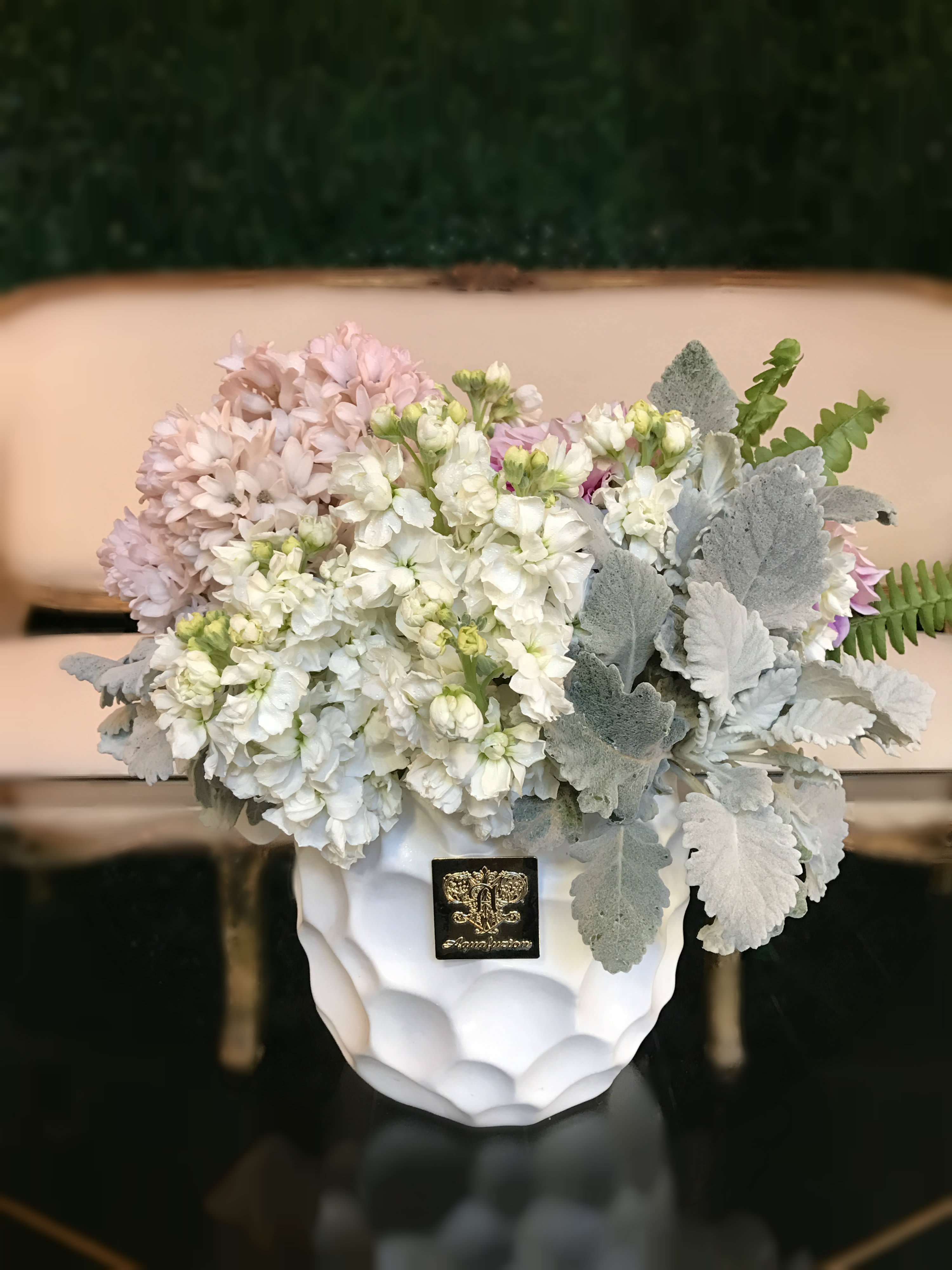 White and pale pink flowers in a white vase with silver foliage