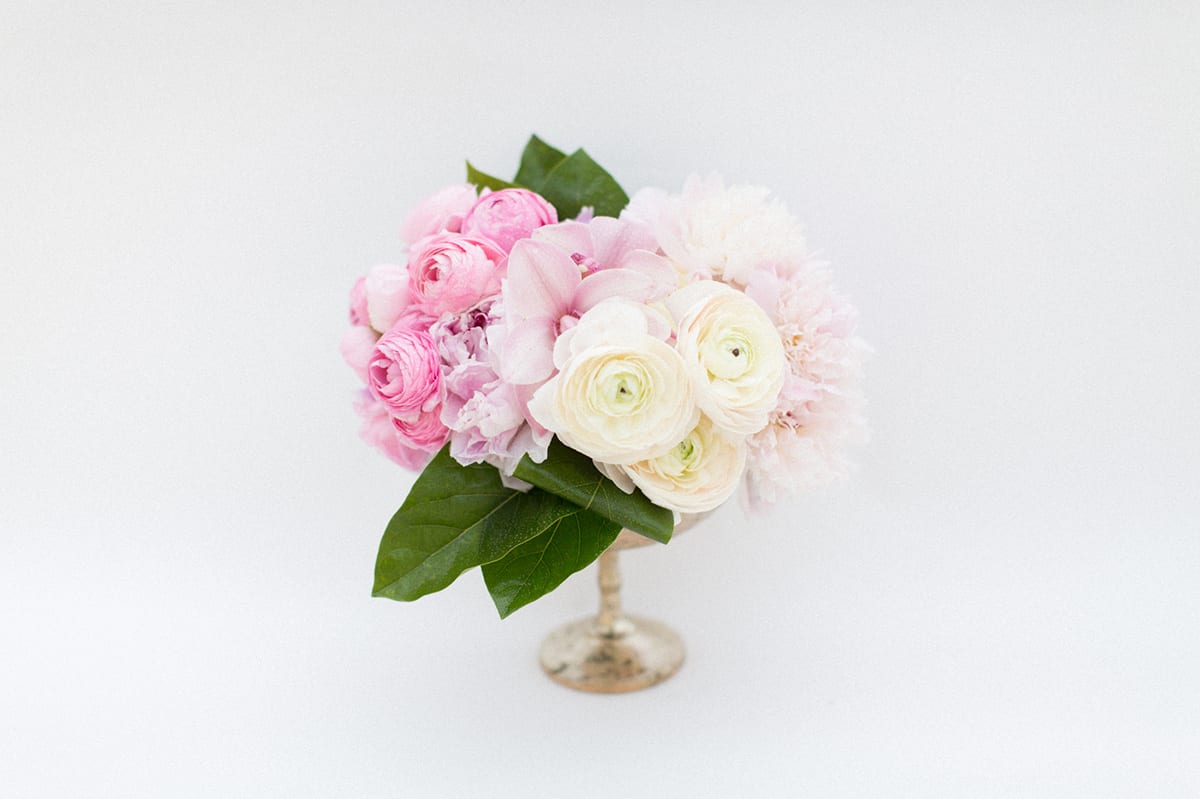 Pink and white floral arrangement in a small pedestal vase