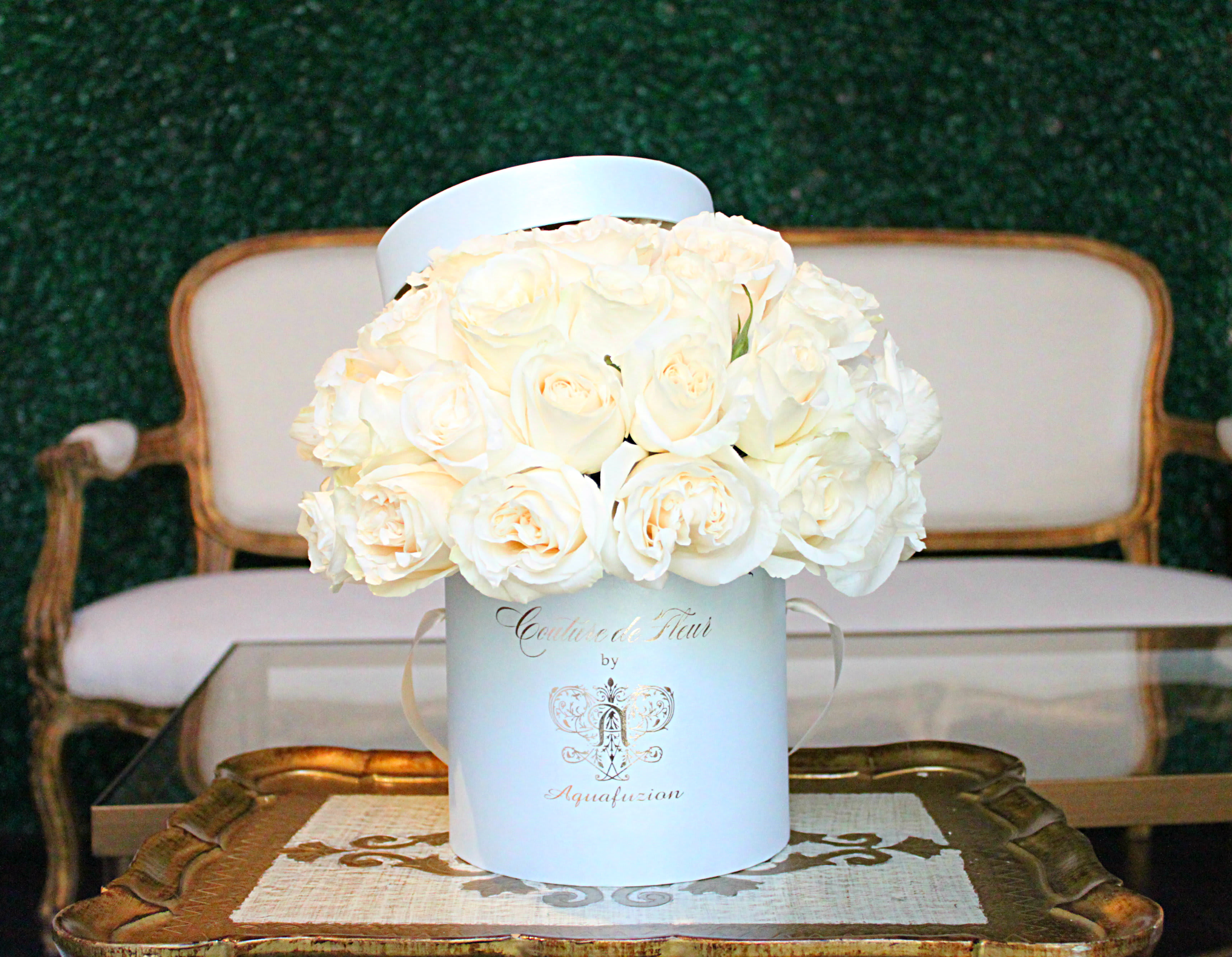 White roses arranged in a round hatbox on a table