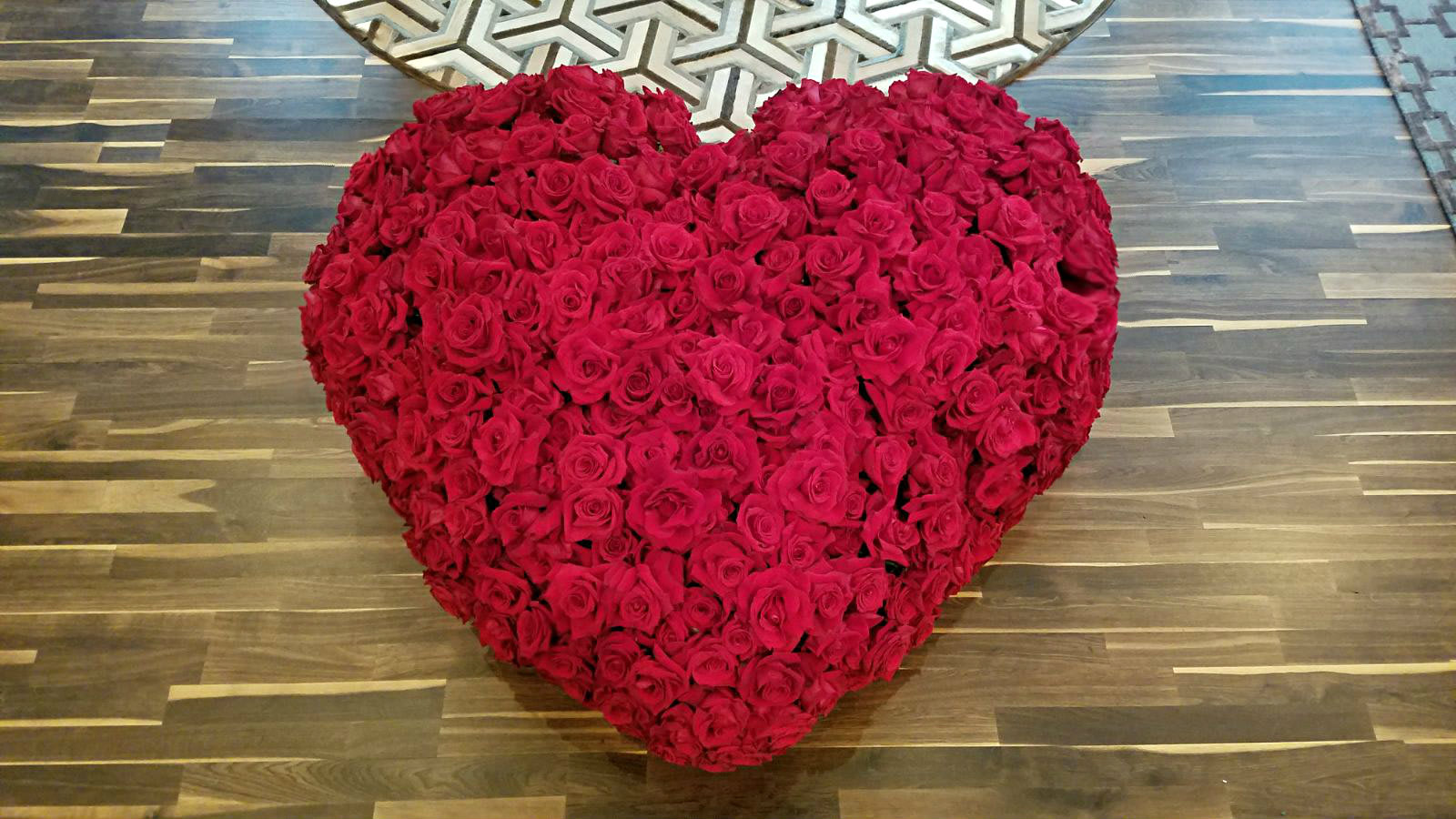 Heart-shaped arrangement of red roses on a wooden floor