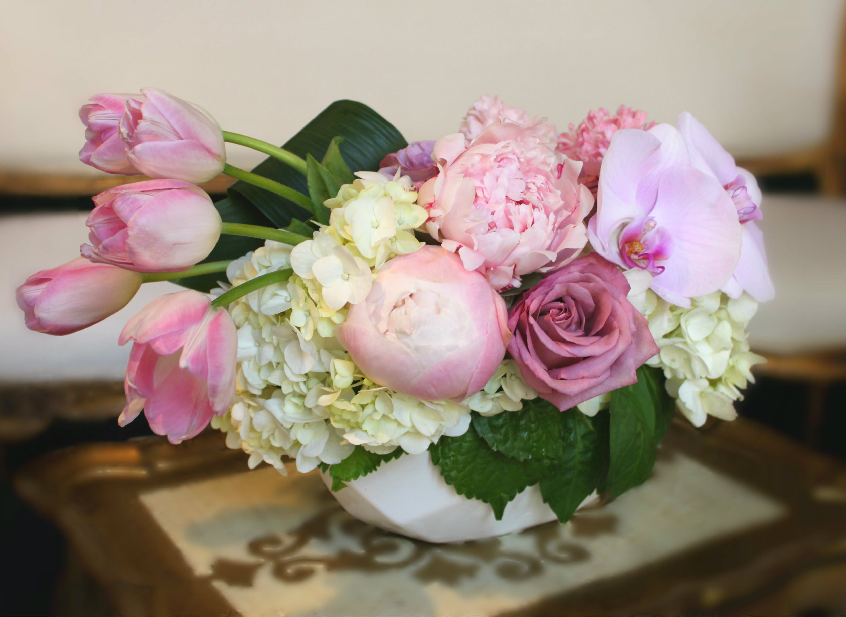 Pink tulips, roses, peonies, and orchids in a white bowl