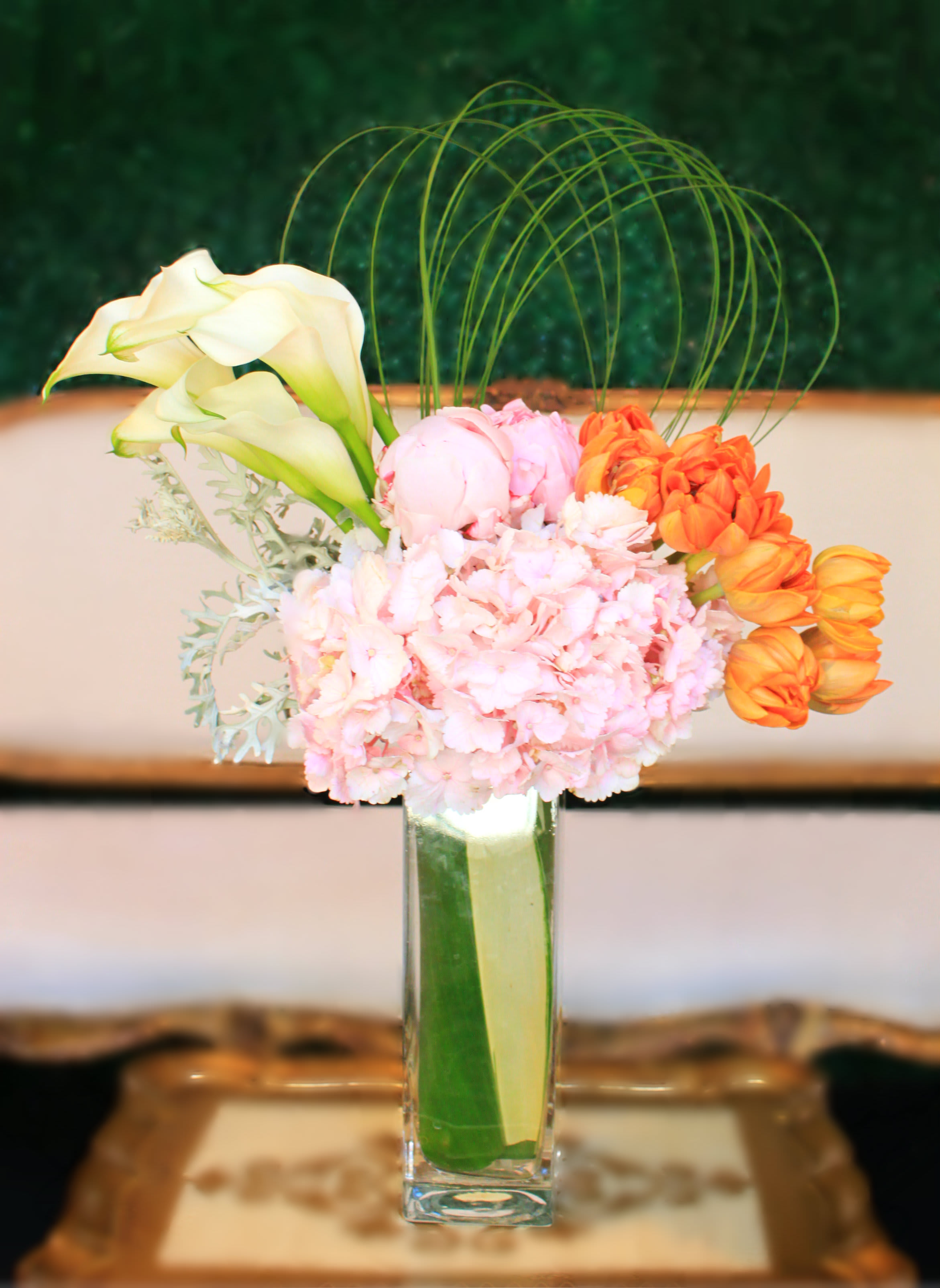 Pink and orange floral arrangement in a tall glass vase