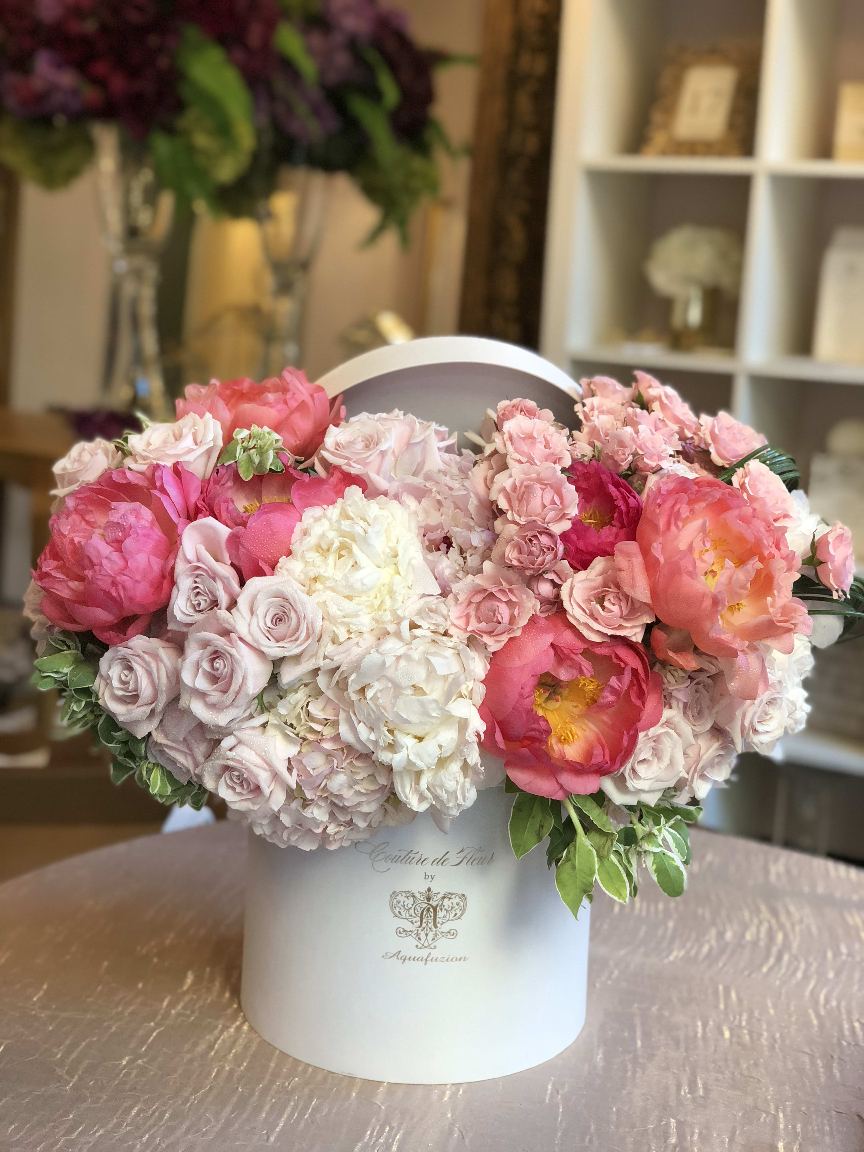 Pink and white floral arrangement in a white hatbox