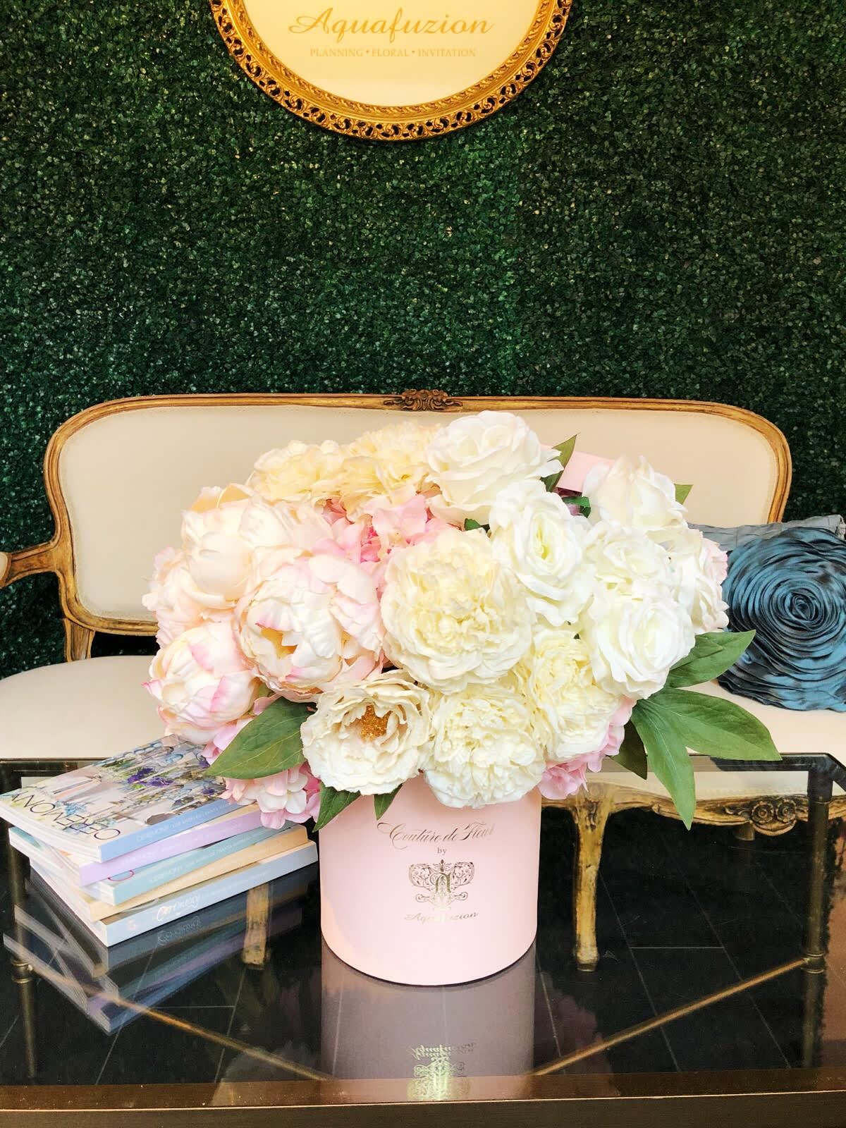 Pink and white flower arrangement in a round box on a table