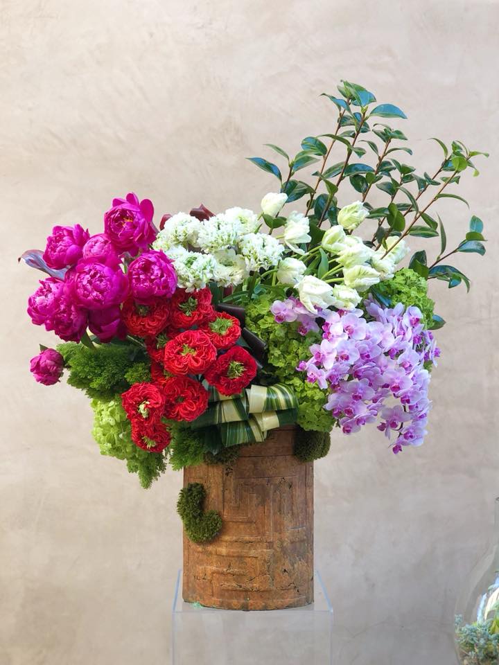 Large mixed bouquet with pink, red, white, and lavender flowers in a wooden container