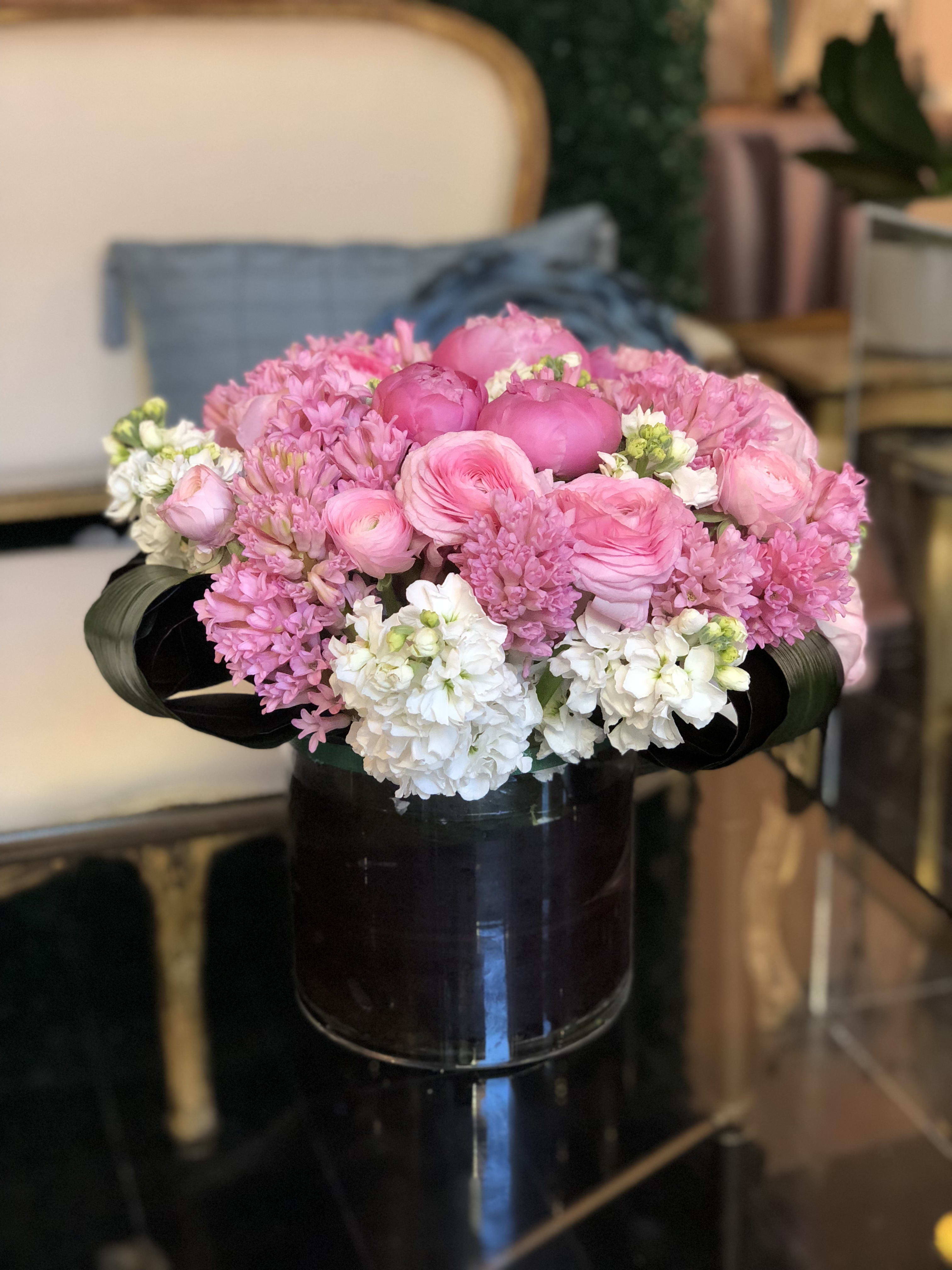 Pink and white flower arrangement in a dark glass vase