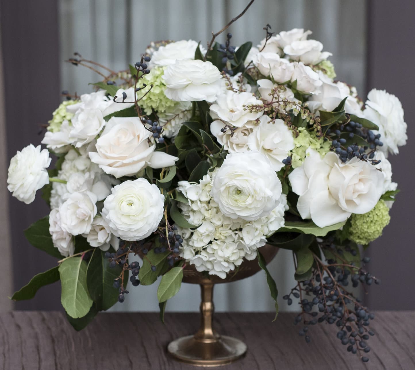 Analeen  - Classic arrangement with cream hydrangeas, cream roses, white ranunculus, and greens in a unique gold vase. 