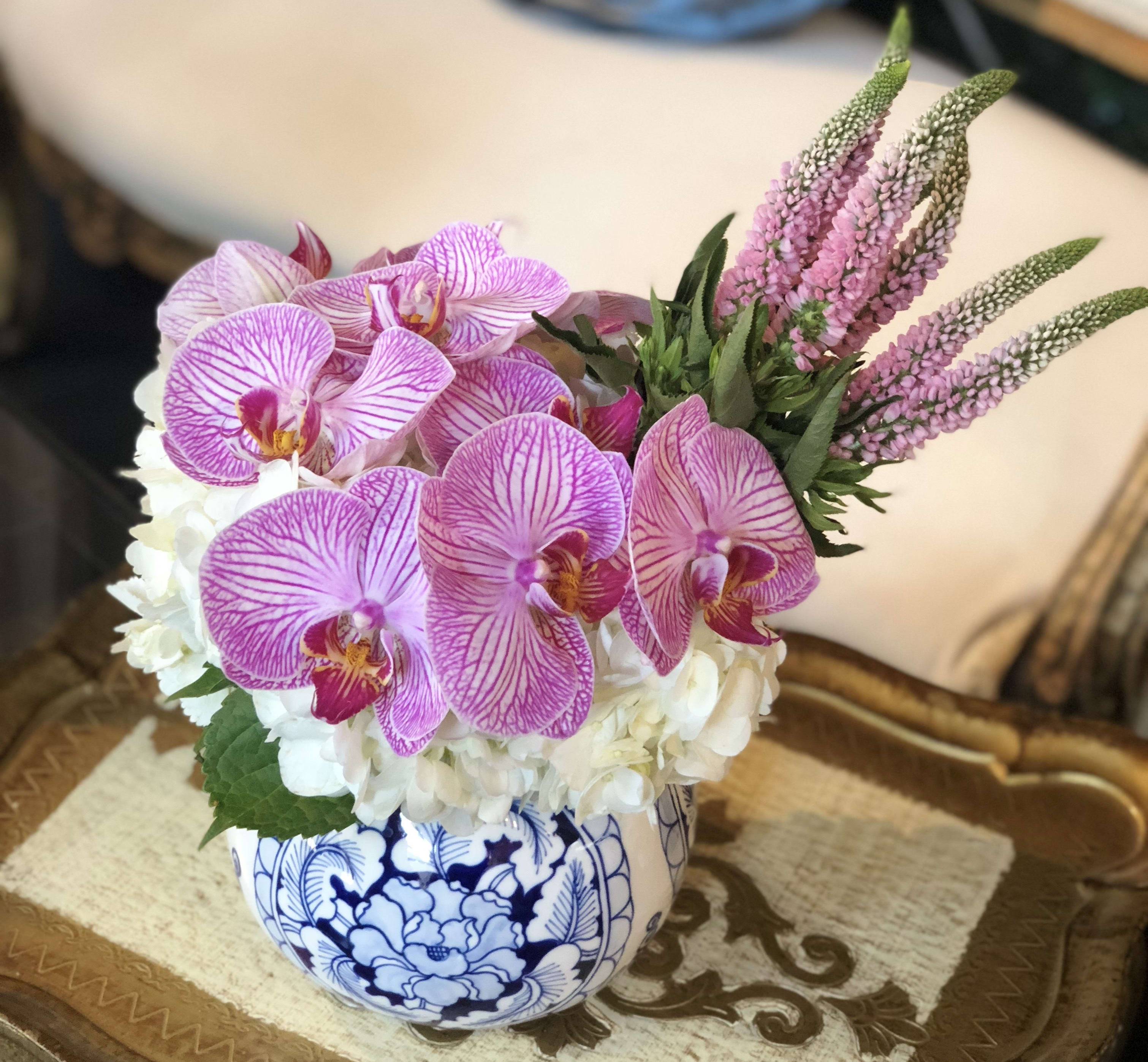 Pink orchids and white hydrangeas in a blue-and-white ceramic bowl