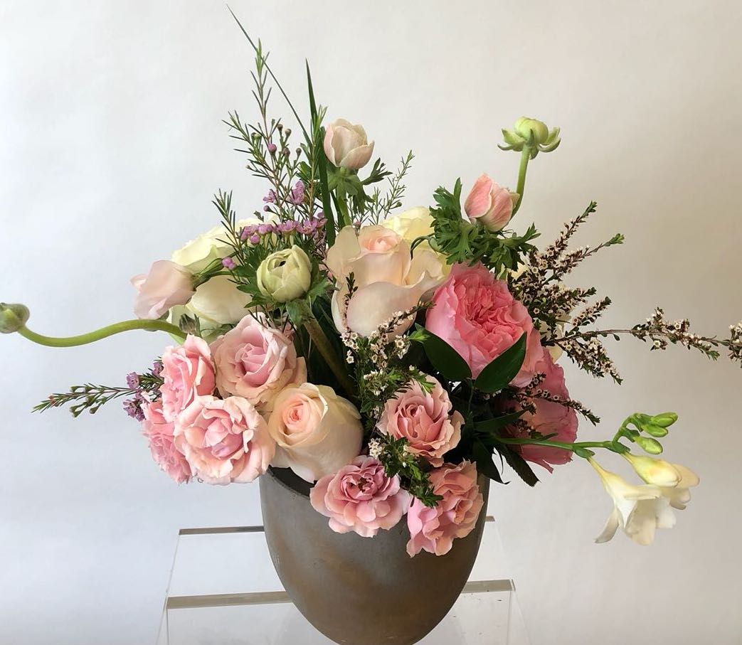 Pink and white floral arrangement in a brown vase