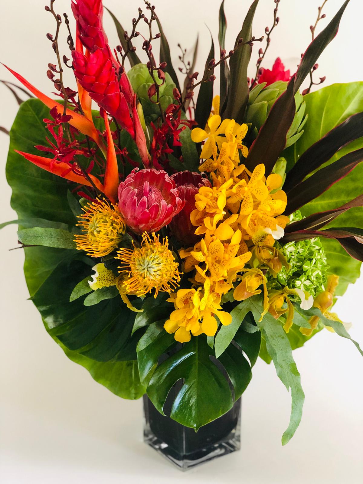 Tropical bouquet with red and yellow flowers in a black vase