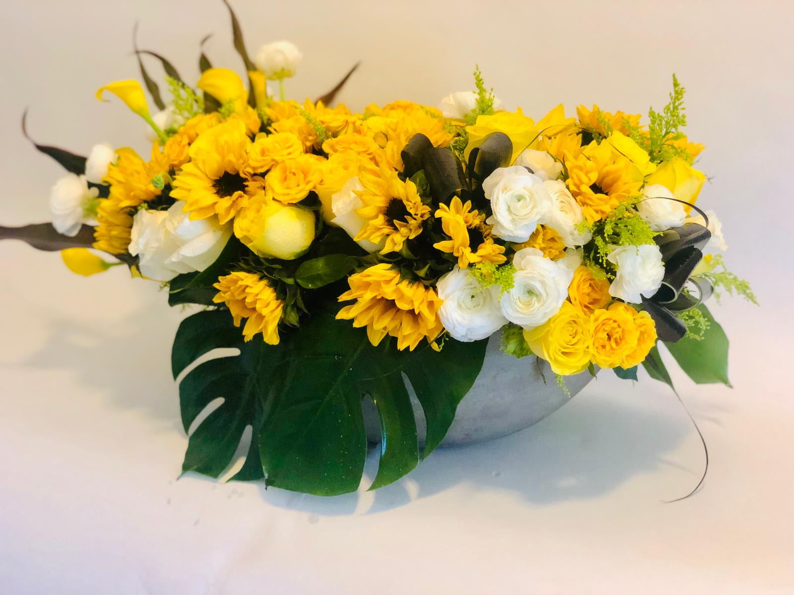 Yellow and white floral arrangement in a low gray bowl