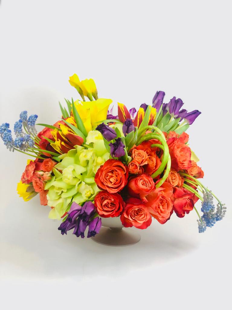 Colorful bouquet of roses, tulips, and orchids in a low vase