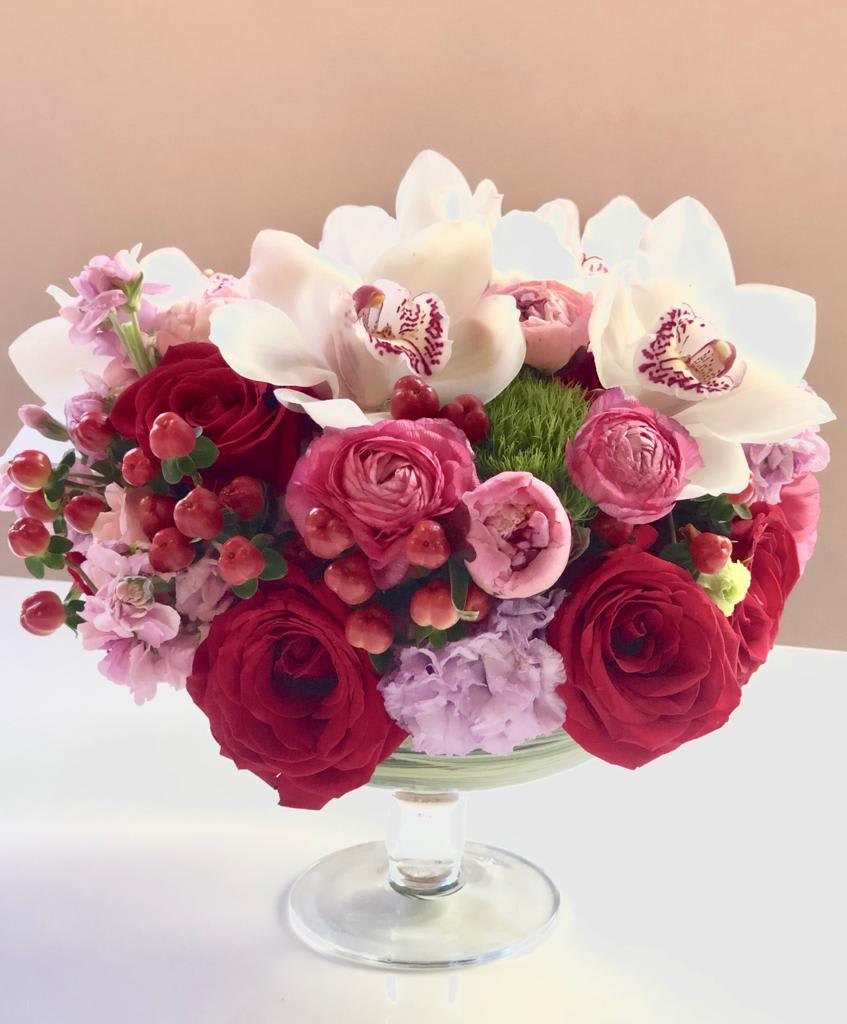 Red and pink bouquet with white orchids in a glass vase