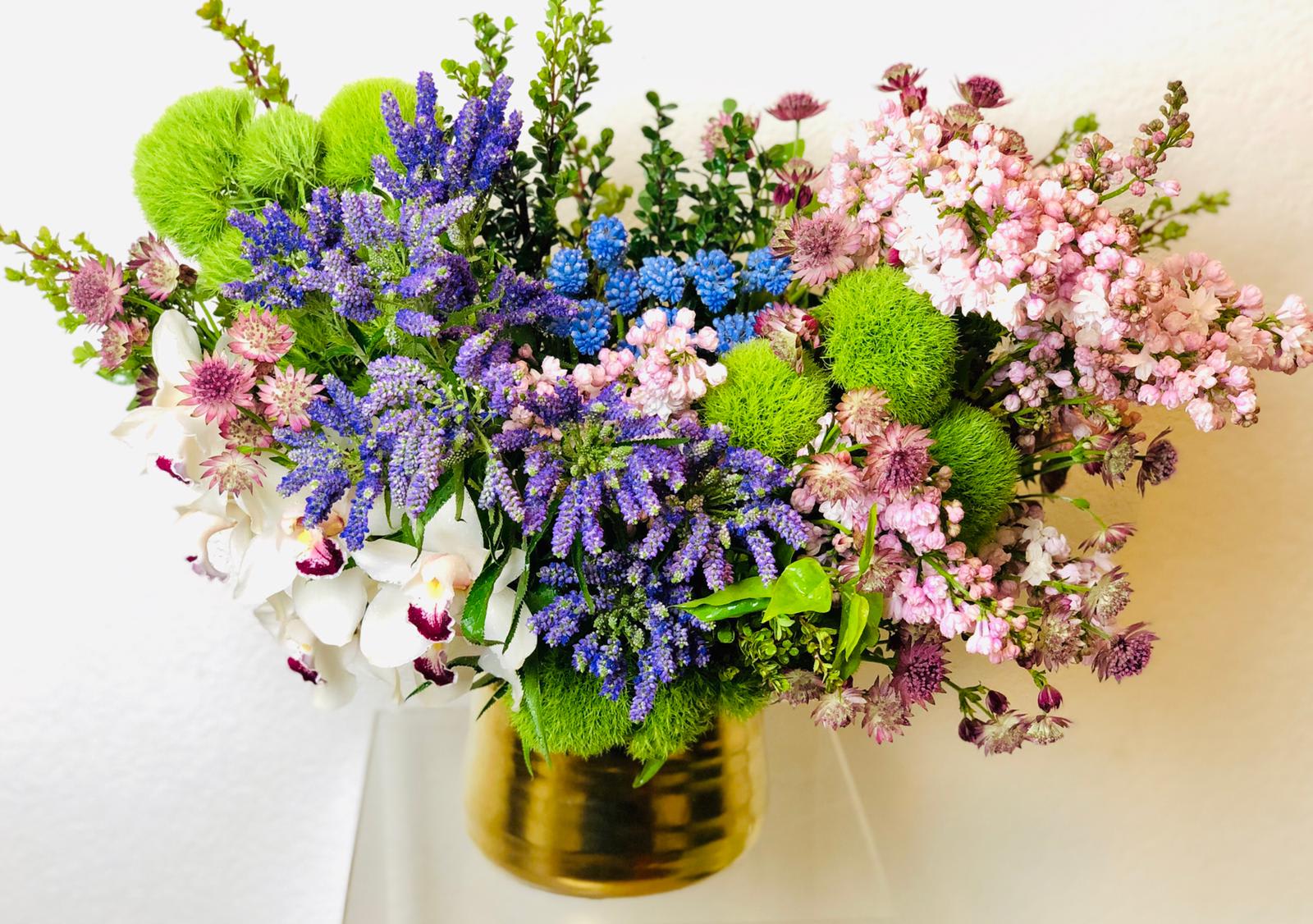 Mixed bouquet with purple, pink, white, and green flowers in a gold vase