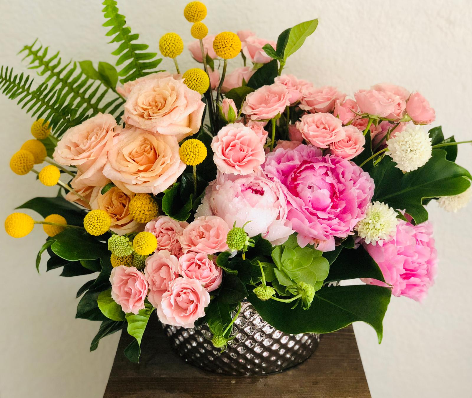 Pink and peach floral arrangement in a silver textured vase