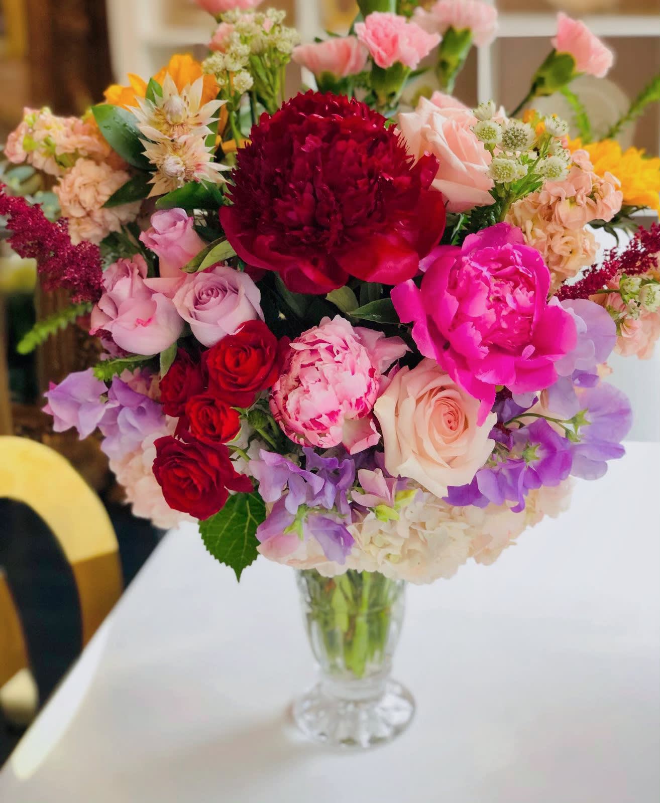 Mixed bouquet of pink, red, and purple flowers in a clear glass vase