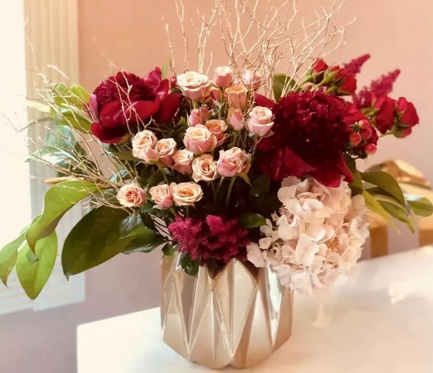 Bouquet of red and blush flowers in a metallic vase
