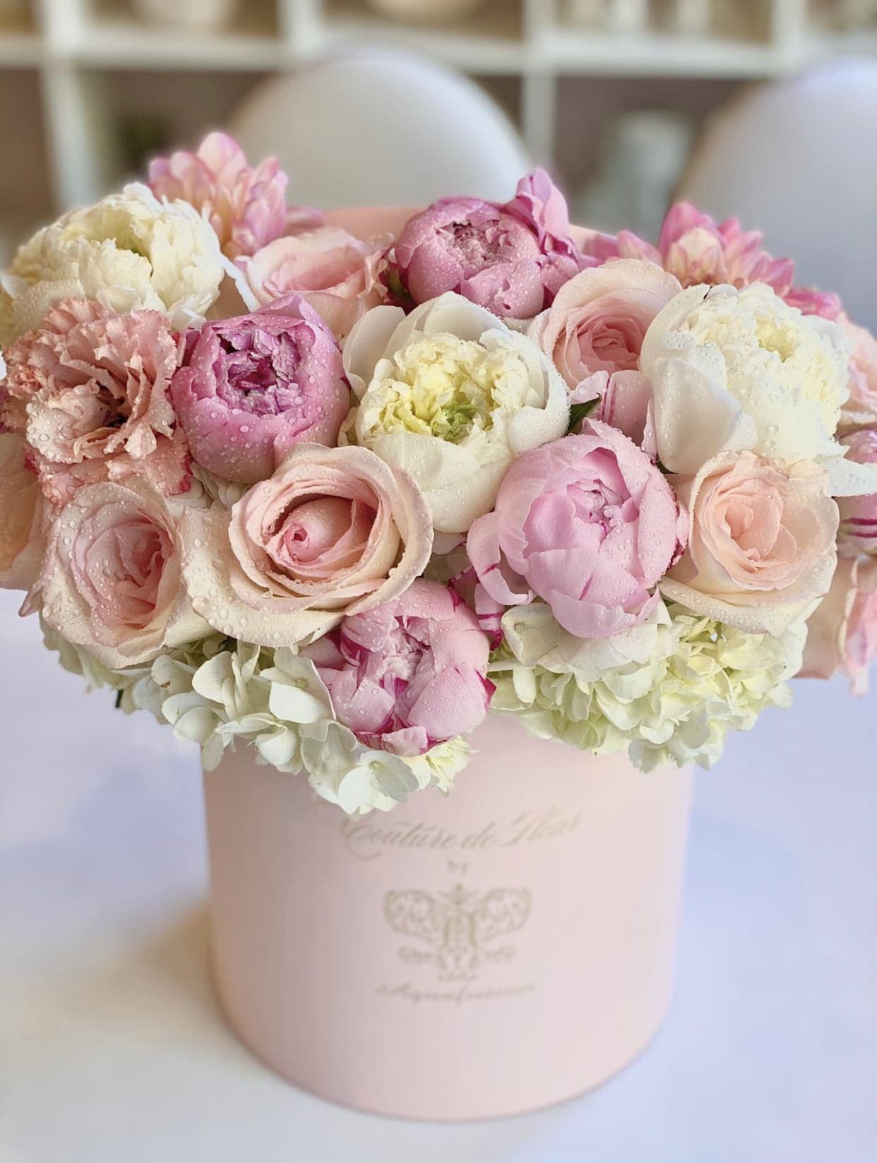 Pink and white bouquet of peonies and roses in a pale pink box