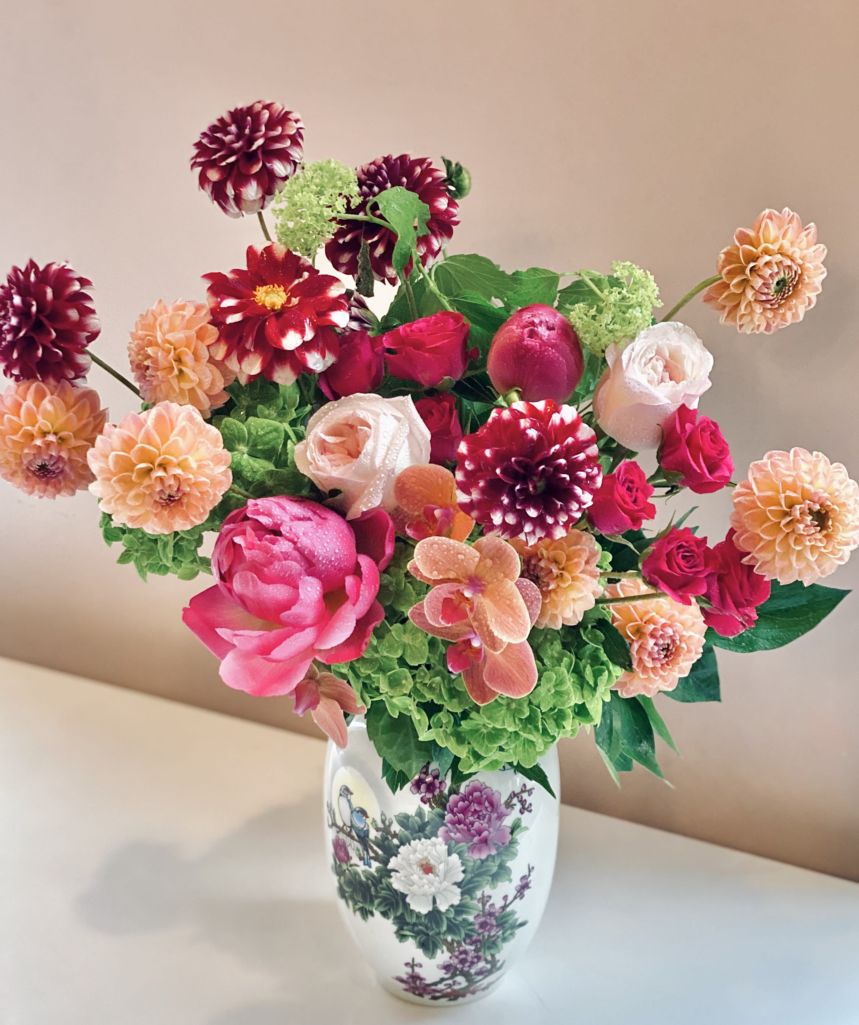 Colorful bouquet of dahlias, roses, and orchids in a decorative vase