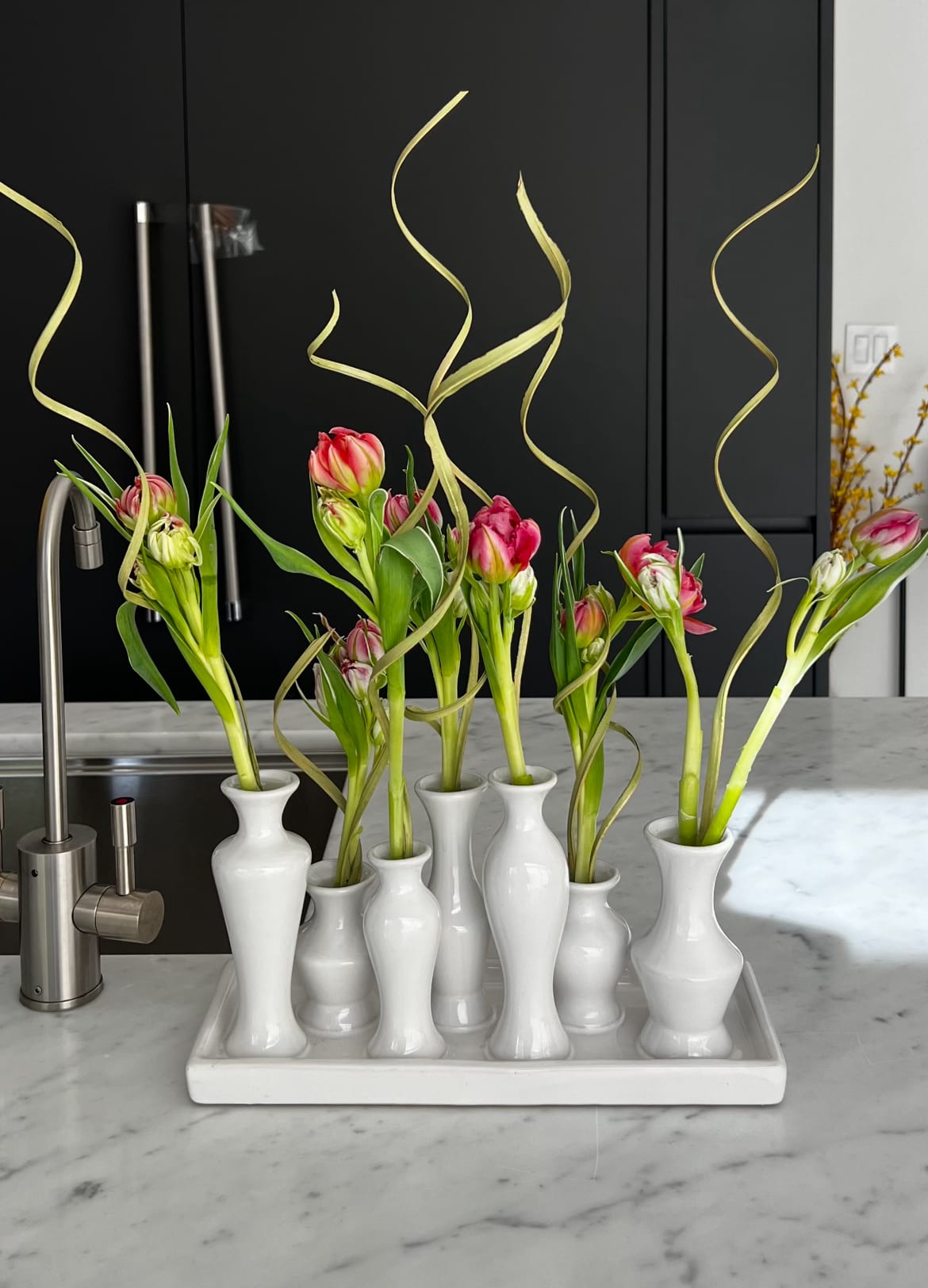 Pink tulips in white bud vases on a tray