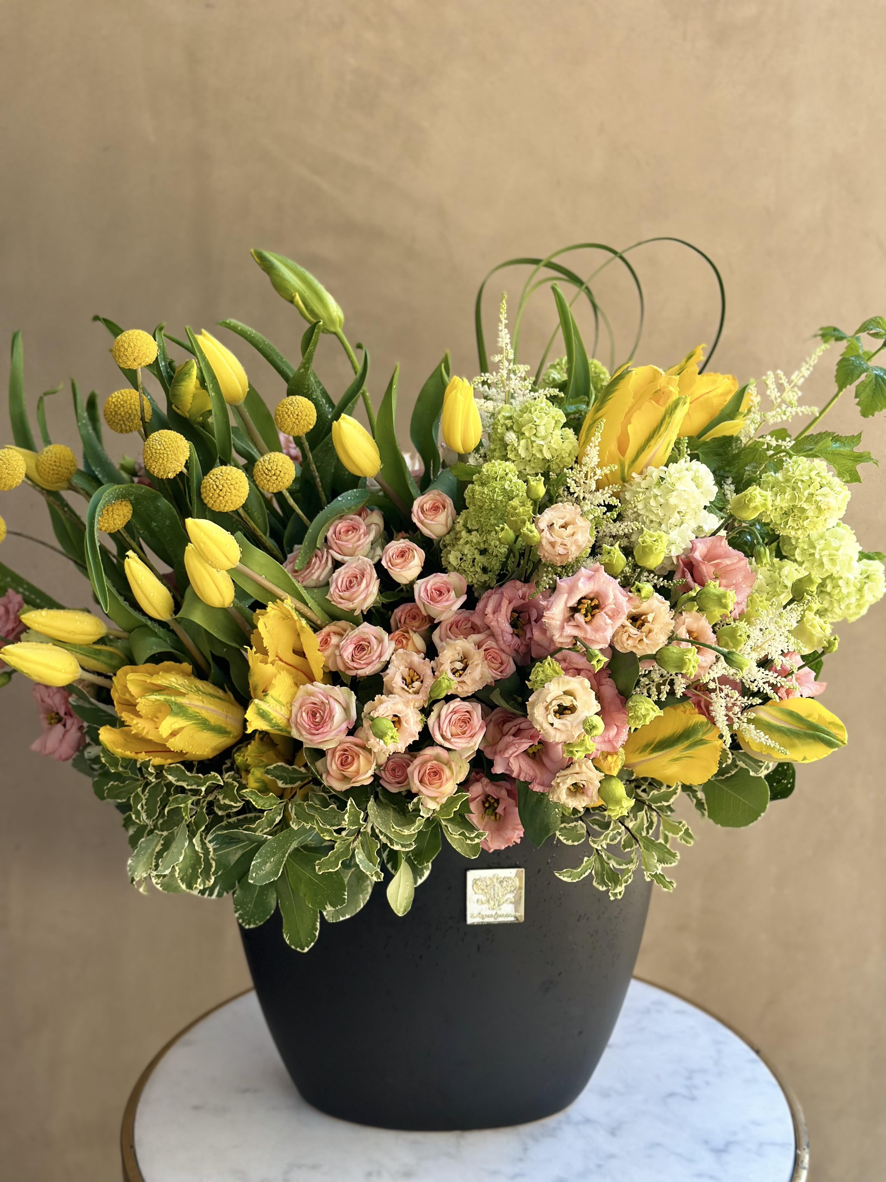 Yellow tulips and pink roses arranged in a black vase