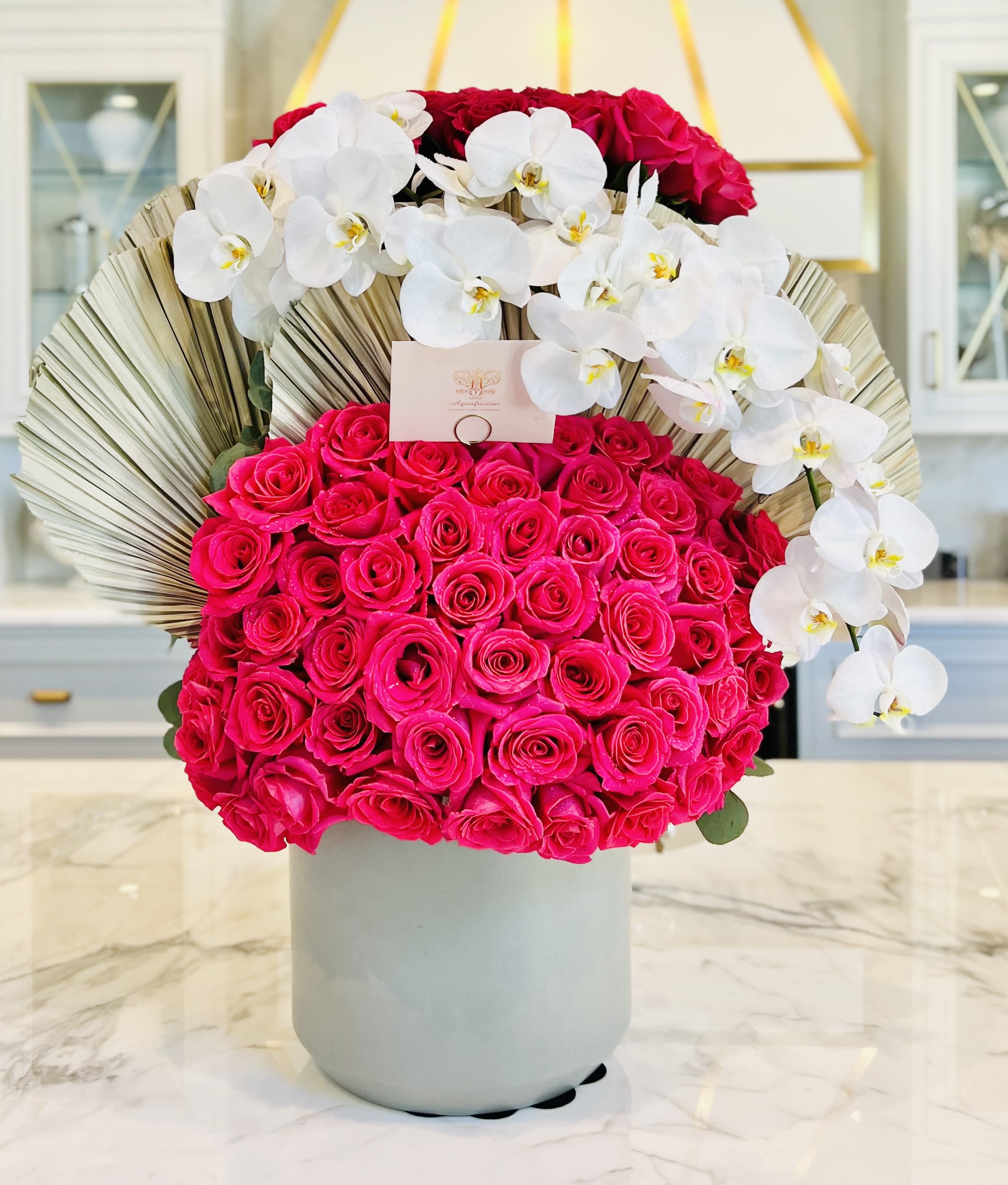 Hot pink roses with white orchids in a gray vase