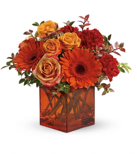Orange and red flowers in a square glass vase
