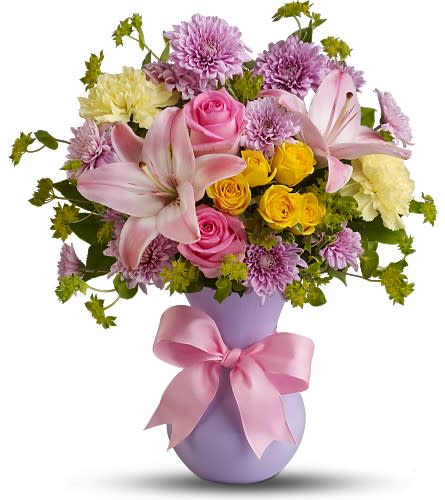 Pink and yellow flower arrangement in a lavender vase with a pink ribbon