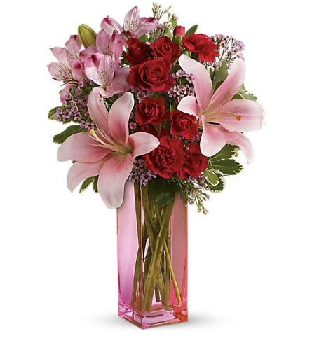 Pink lilies and red roses in a tall pink glass vase