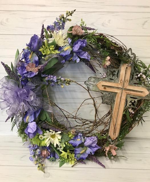 Floral wreath with purple and white flowers and a wooden cross
