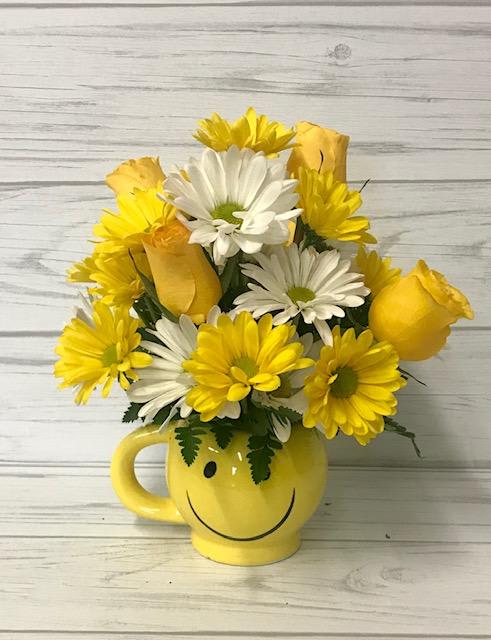 Yellow and white daisy bouquet in a smiley-face mug