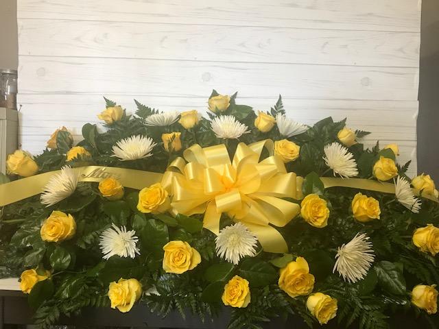 Yellow roses and white spider mums arranged with a yellow ribbon bow