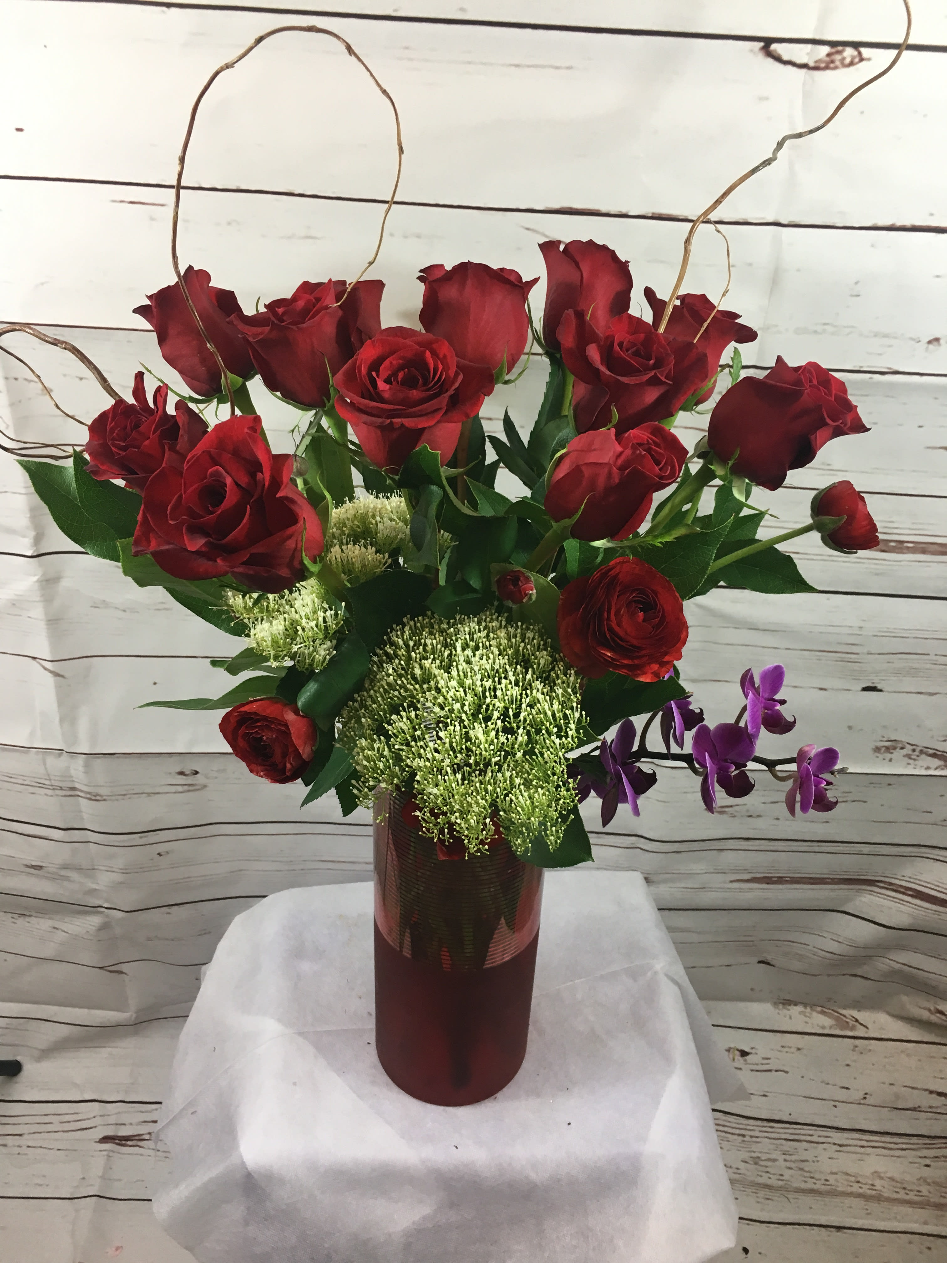 Red roses in a tall vase with purple orchids