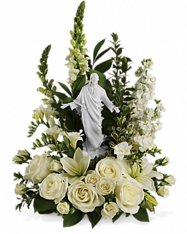 White floral arrangement with a small religious statue in the center