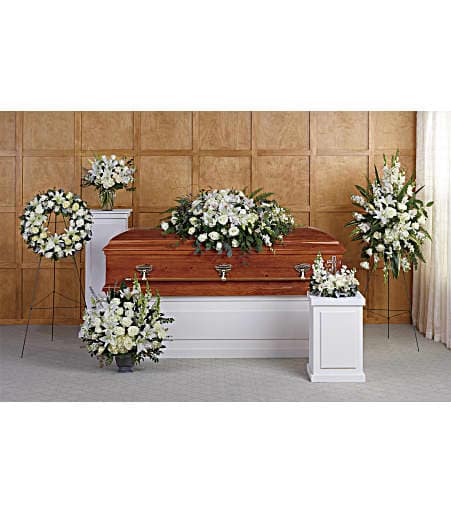 White funeral casket surrounded by white floral sprays and wreaths