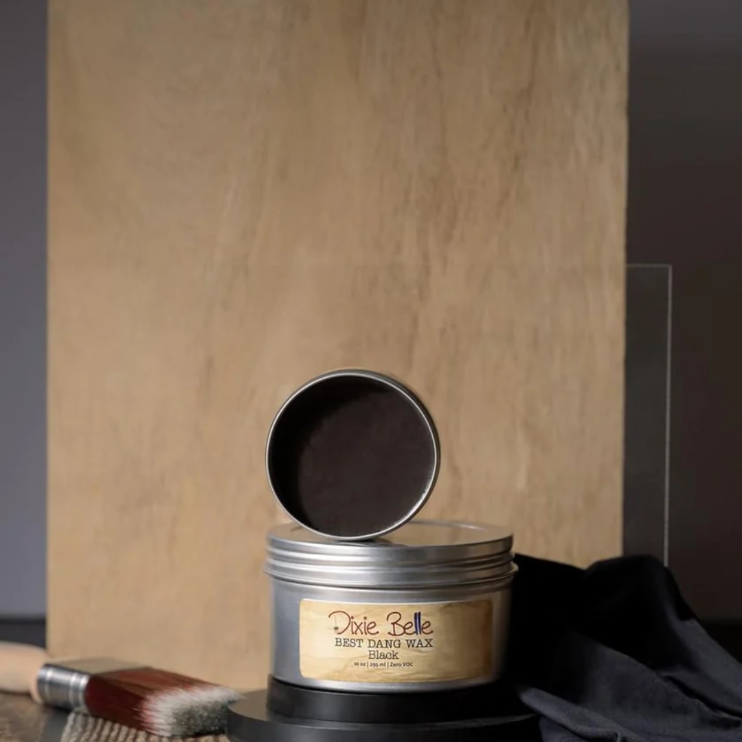 Tin of black wax with a brush beside it on a tabletop
