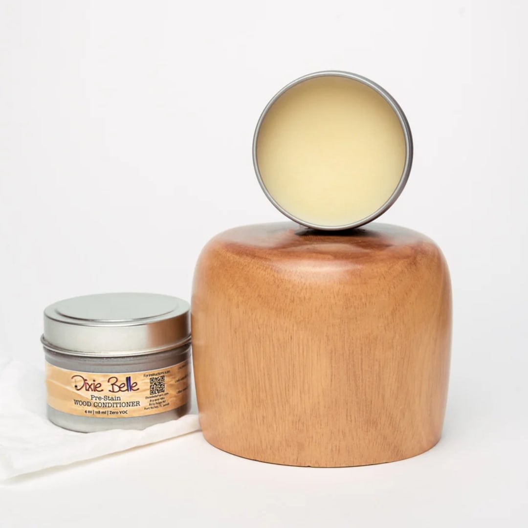 Wooden candle holder with a round tin candle and a small metal tin beside it