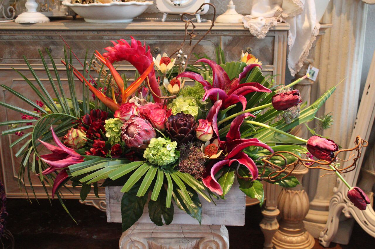 Tropical floral arrangement with pink lilies and protea in a rectangular container