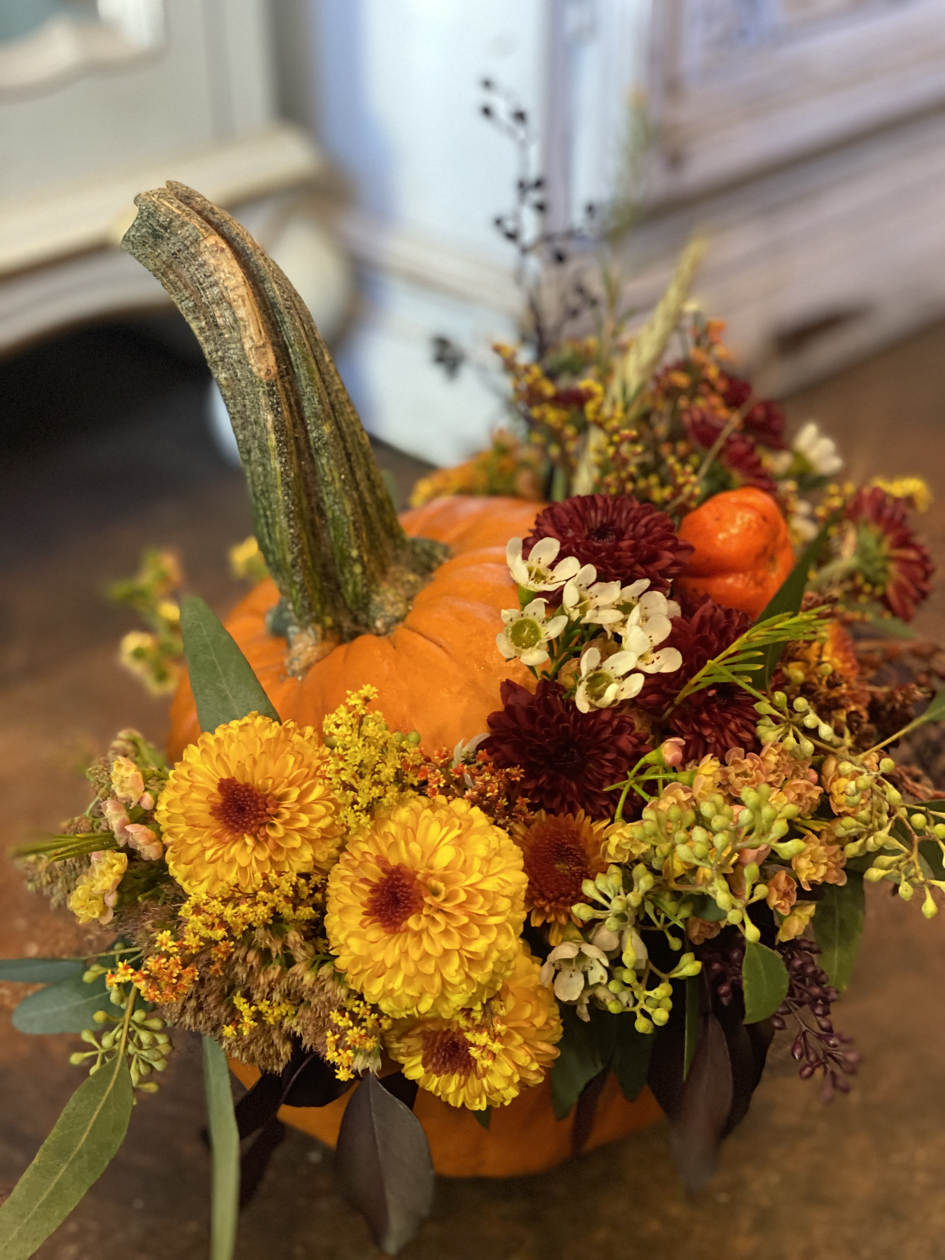 Pumpkin centerpiece with yellow and burgundy flowers