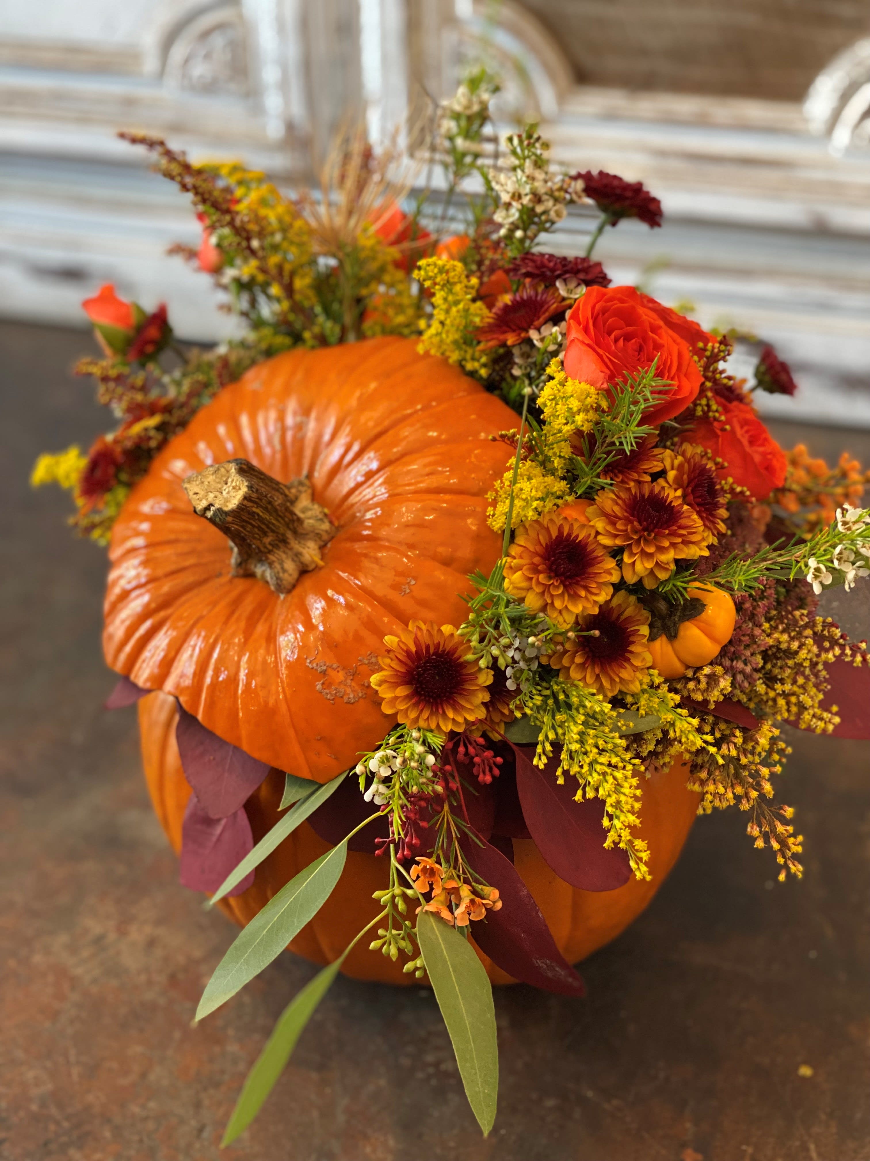 Pumpkin decorated with orange and burgundy flowers