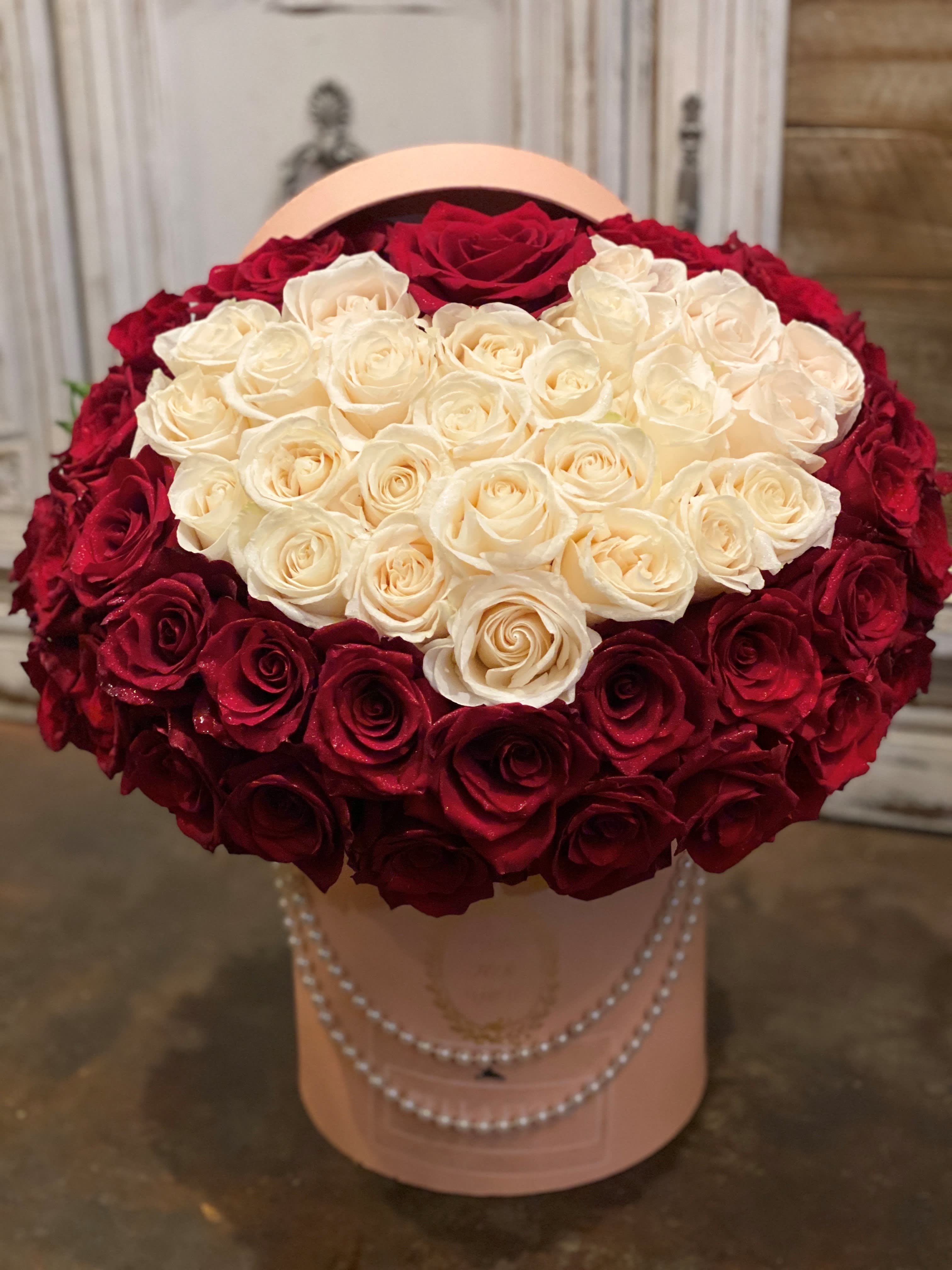 Heart-shaped bouquet of red and white roses in a pink hatbox