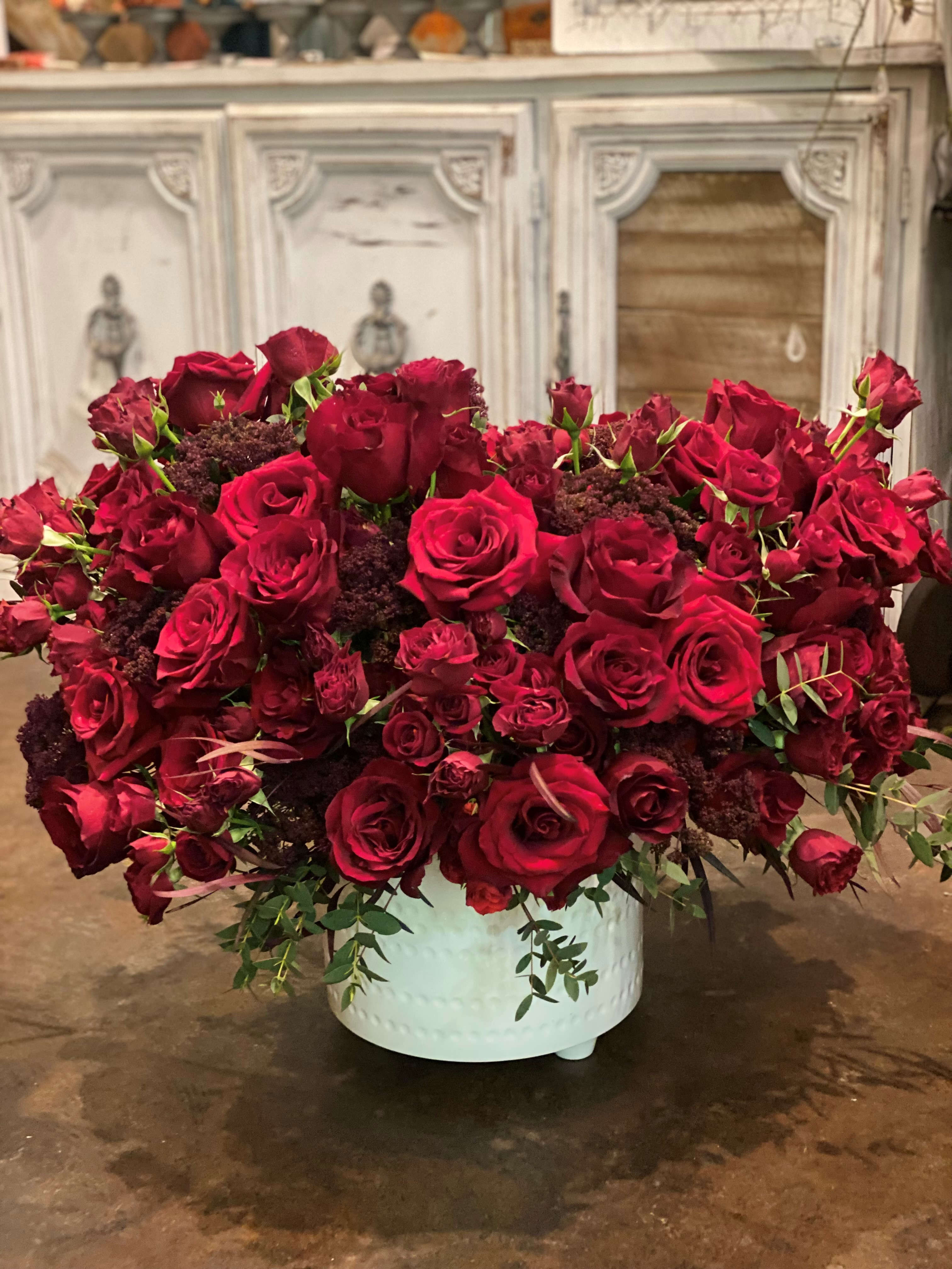 Large arrangement of red roses in a white container