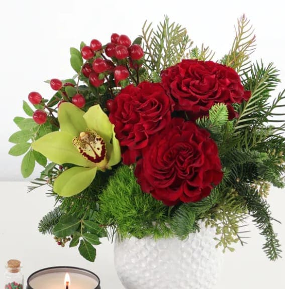 Red roses and a green orchid in a white vase