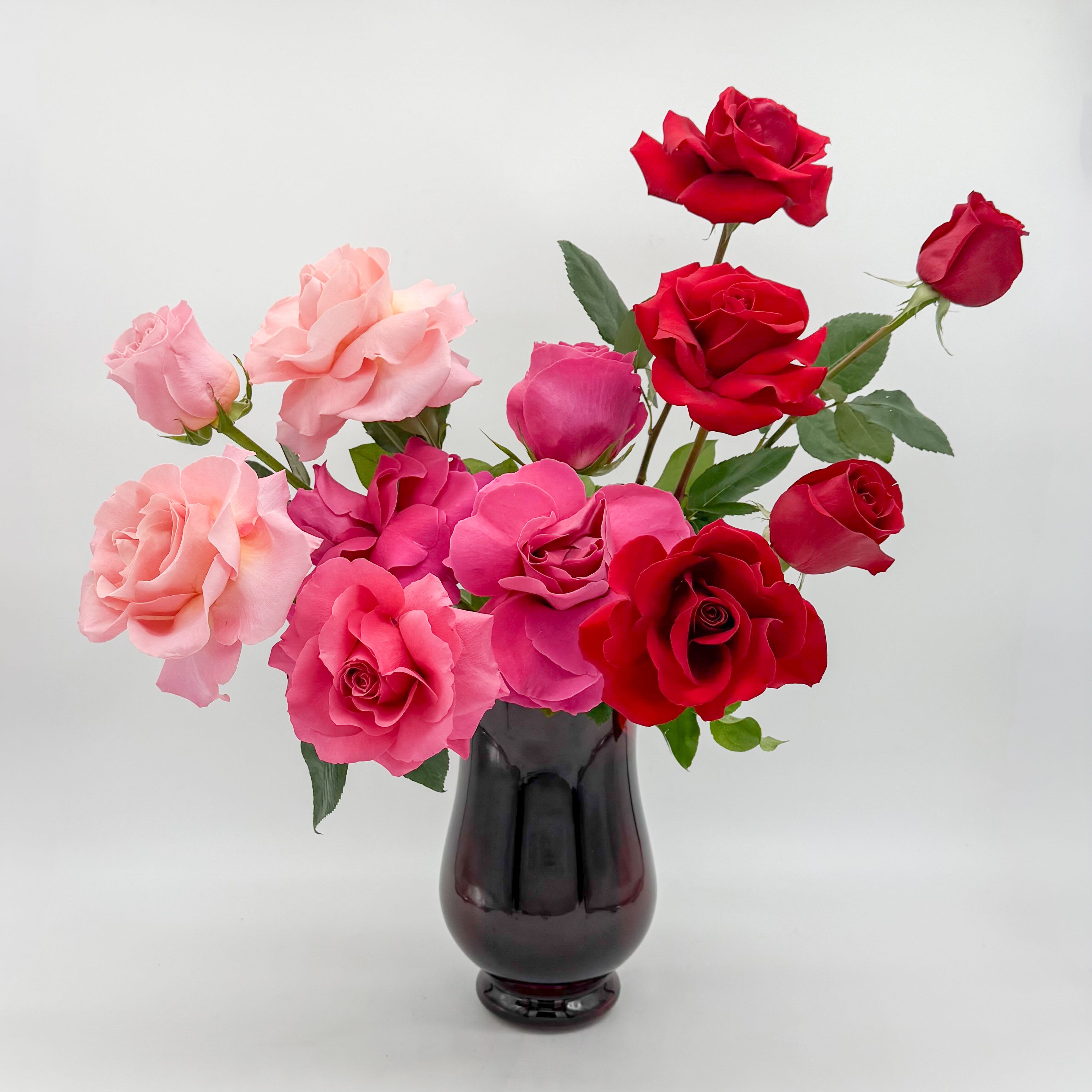 Pink and red roses arranged in a dark glass vase